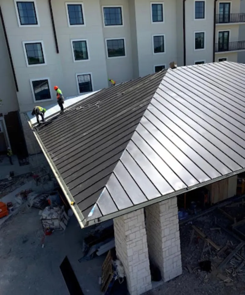 Crew installing standing seam metal roof panels on a commercial project in Shiloh